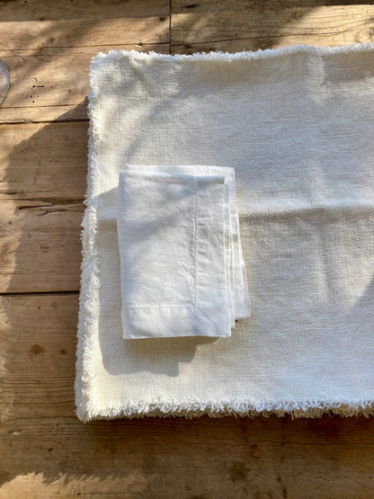 Folded white napkin on stack of Maya linen placemats