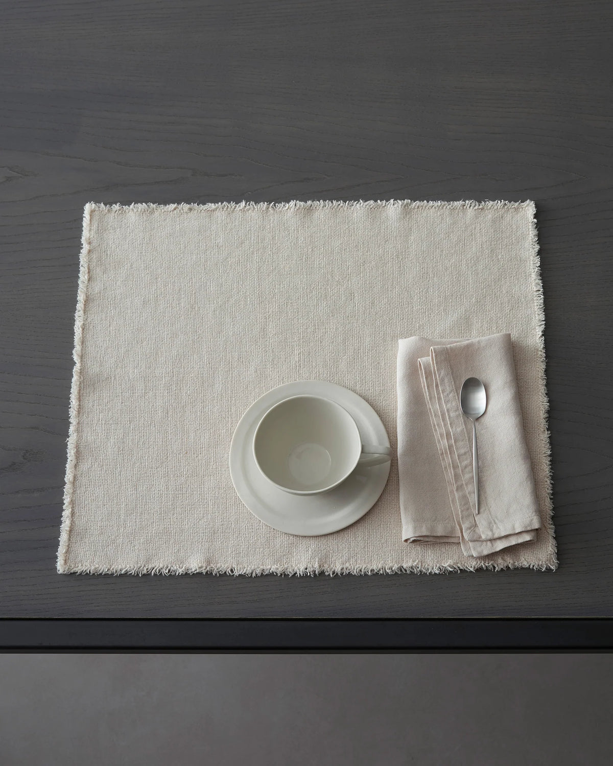 Table setting with a white bowl, napkin, and spoon on Maya linen placemat
