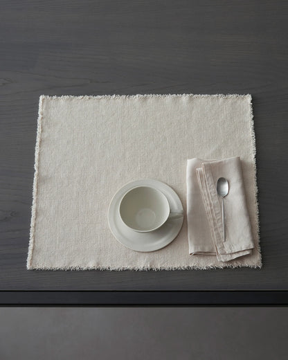 Table setting with a white bowl, napkin, and spoon on Maya linen placemat