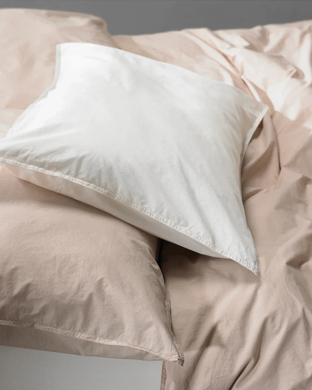 White pillow on a beige comforter with a neutral background