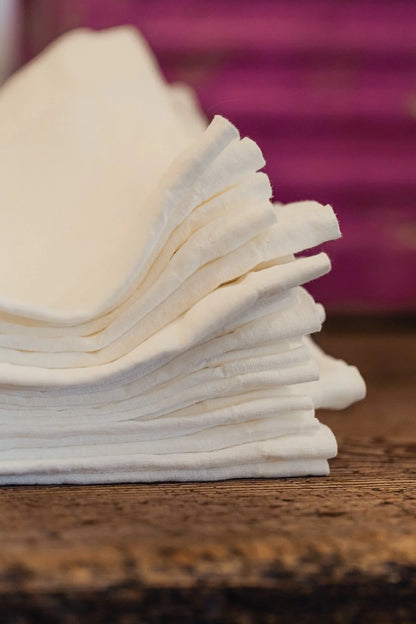 Stack of white napkins on a wooden surface with a blurred purple background