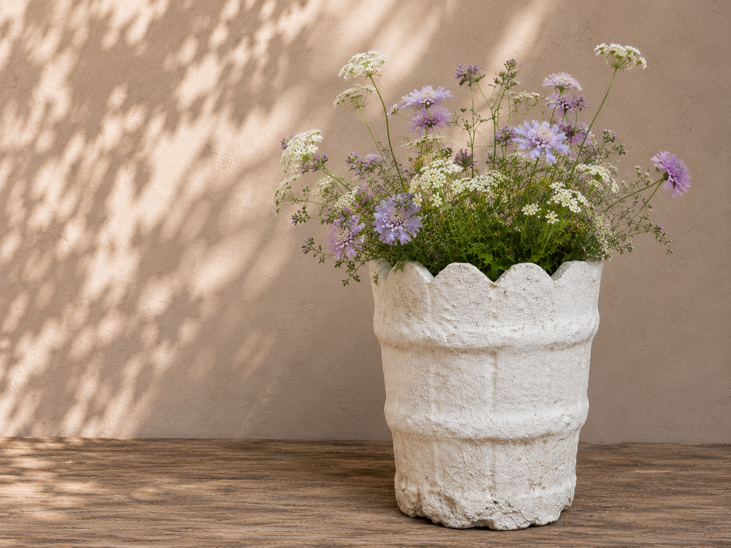 Decorative white planter with flowers against a beige wall