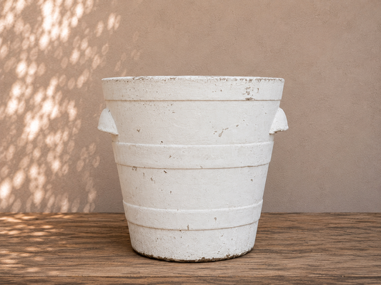 White textured planter on a wooden surface with a beige wall background