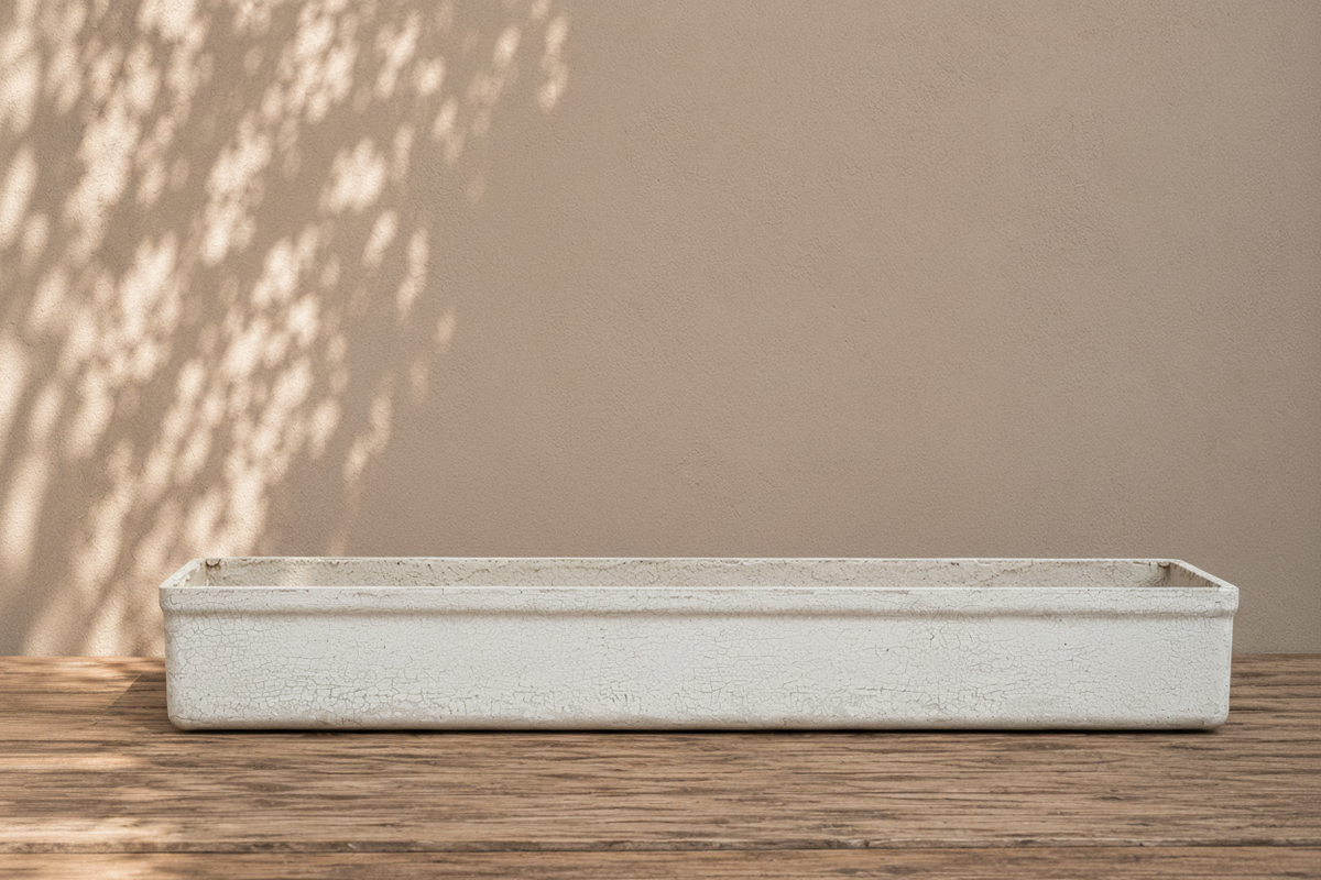 Rectangular concrete planter on a wooden surface with a beige wall in the background