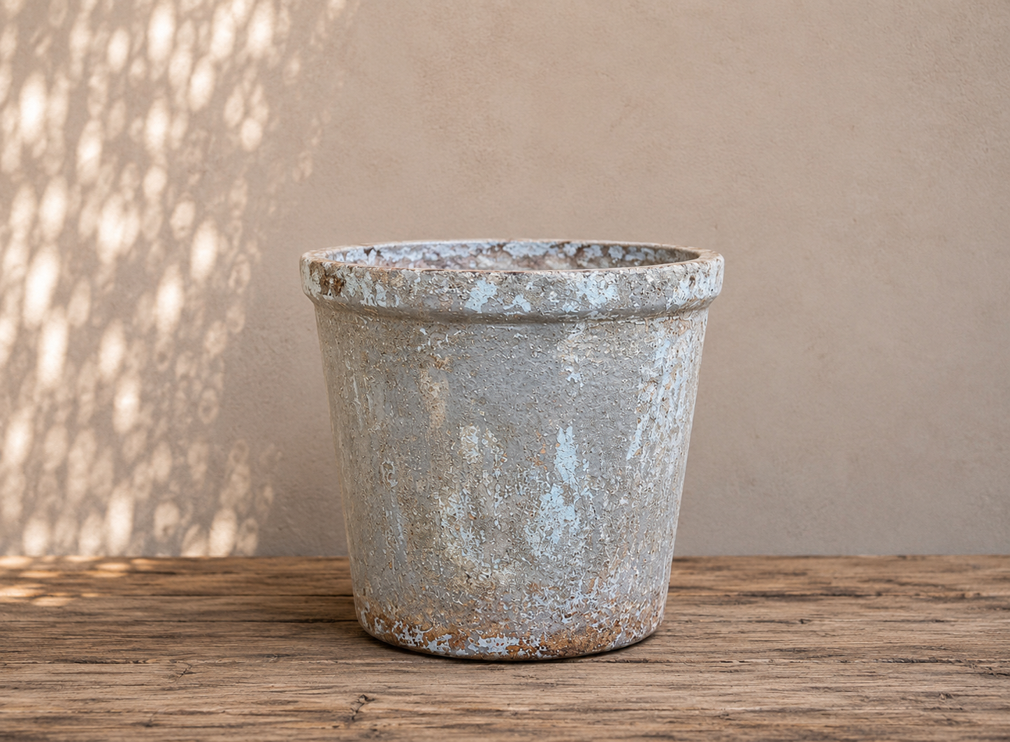Vintage planter on a wooden surface with a neutral background